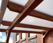 Terrassenüberdachung in Fichte/Tanne Leimholz lasiert -walnuss-. Dacheindeckung mit weißen, schlagfesten Polycarbonat-Stegplatten